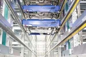Herzstück der Logistikerweiterung 2014: Im vollautomatischen Shuttlelager fahren 375 Shuttles durch die 15 jeweils 60 m langen Regalgassen. Wenn die Artikelansprache es erfordert, wechseln die Shuttles (siehe Bild) über Shuttleheber die Lagerebenen und haben somit auf insgesamt 200.000 Behälter mit bis zu 800.000 Lagerplätzen Zugriff. Herzstück der Logistikerweiterung 2014: Im vollautomatischen Shuttlelager fahren 375 Shuttles durch die 15 jeweils 60 m langen Regalgassen. Wenn die Artikelansprache es erfordert, wechseln die Shuttles (siehe Bild) über Shuttleheber die Lagerebenen und haben somit auf insgesamt 200.000 Behälter mit bis zu 800.000 Lagerplätzen Zugriff.