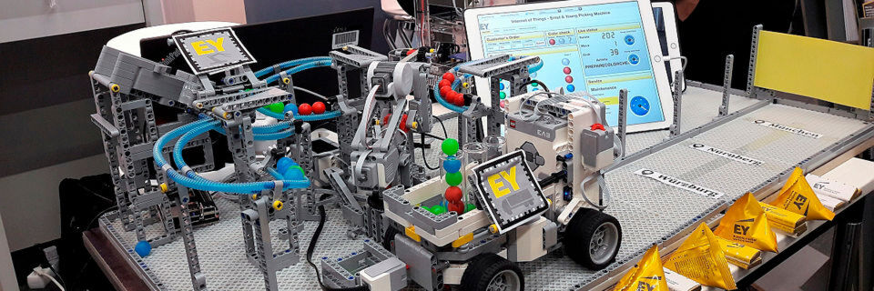 In dieser IoT-Demo-Station von Ernst & Young wird ein „Lastwagen“ mit bunten Kugeln beladen, die aus einer Beladungsmaschine kommen. Diese „Picking Machine“ wird im Bildschirm dahinter angezeigt: Das ganze Modell ist mit Sensoren gespickt, deren Daten von der PTC-Software ThingWorx erfasst und angezeigt werden. In dieser IoT-Demo-Station von Ernst & Young wird ein „Lastwagen“ mit bunten Kugeln beladen, die aus einer Beladungsmaschine kommen. Diese „Picking Machine“ wird im Bildschirm dahinter angezeigt: Das ganze Modell ist mit Sensoren gespickt, deren Daten von der PTC-Software ThingWorx erfasst und angezeigt werden.
