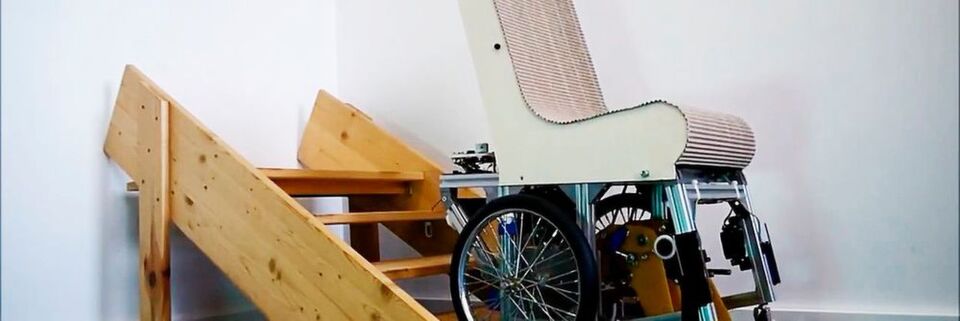 Ein Demonstrator-Modell des Assist Mobil während des Treppensteigens; die Beine befinden sich unterhalb des Rollstuhls und schieben ihn von Stufe zu Stufe. Ein Demonstrator-Modell des Assist Mobil während des Treppensteigens; die Beine befinden sich unterhalb des Rollstuhls und schieben ihn von Stufe zu Stufe.