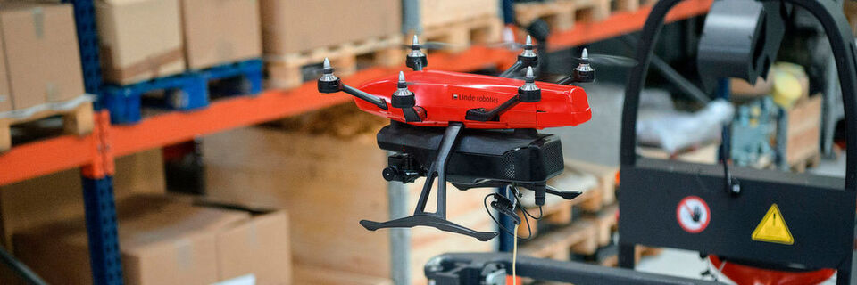 Die „Flybox“ wird bei ihrem Inventureinsatz von einem Linde L-Matic geführt. Drohne und Robotikgerät sind über einen Spannungswandler sowie ein sich selbst justierendes Kabel miteinander verbunden. Die „Flybox“ wird bei ihrem Inventureinsatz von einem Linde L-Matic geführt. Drohne und Robotikgerät sind über einen Spannungswandler sowie ein sich selbst justierendes Kabel miteinander verbunden.