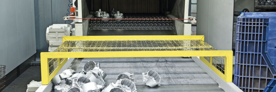 Aluminiumdruckgussteile am Auslauf einer Drahtgurt-Strahlanlage. Mit diesem Anlagentyp lassen sich Massenteile kontinuierlich mit Aluminium strahlen. Aluminiumdruckgussteile am Auslauf einer Drahtgurt-Strahlanlage. Mit diesem Anlagentyp lassen sich Massenteile kontinuierlich mit Aluminium strahlen.