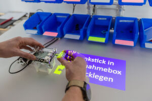 Indem der Assistent frei über dem Arbeitsplatz montiert wird, überwacht er mittels Kameras, Projektoren und weiterer Sensoren die manuelle Produktion, leitet durch den Fertigungsprozess, kontrolliert, ob jeder Handgriff korrekt und nach Vorgabe erfolgt, schult bei Bedarf direkt während der Fertigung und sorgt so für eine deutlich verbesserte und gleichbleibende Qualität. Indem der Assistent frei über dem Arbeitsplatz montiert wird, überwacht er mittels Kameras, Projektoren und weiterer Sensoren die manuelle Produktion, leitet durch den Fertigungsprozess, kontrolliert, ob jeder Handgriff korrekt und nach Vorgabe erfolgt, schult bei Bedarf direkt während der Fertigung und sorgt so für eine deutlich verbesserte und gleichbleibende Qualität.