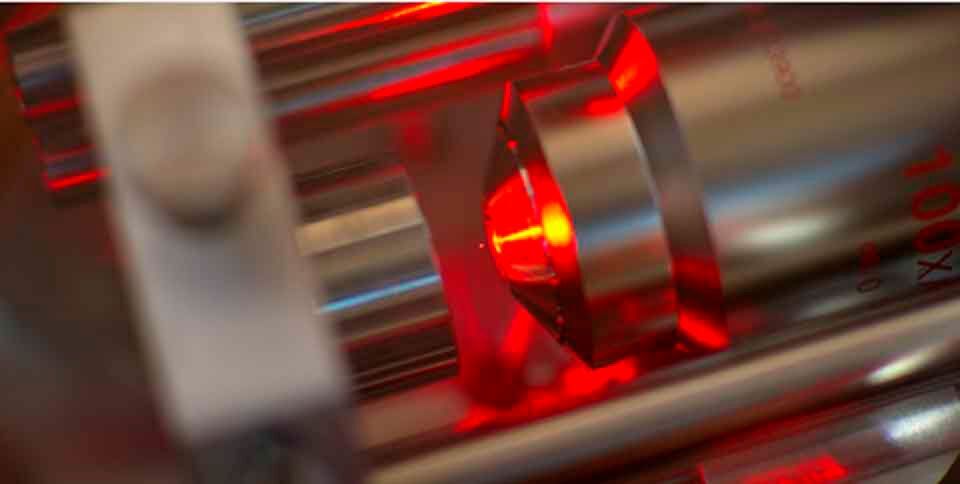Ein Mikroskop-Objektiv (rechts) bündelt Laserlicht zu einer optischen Pinzette, von der ein Nanokügelchen (winziger roter Punkt in der Bildmitte) in der Schwebe gehalten wird. (Bild: ETH Zürich / Erik Hebestreit und Vijay Jain) Ein Mikroskop-Objektiv (rechts) bündelt Laserlicht zu einer optischen Pinzette, von der ein Nanokügelchen (winziger roter Punkt in der Bildmitte) in der Schwebe gehalten wird. (Bild: ETH Zürich / Erik Hebestreit und Vijay Jain)