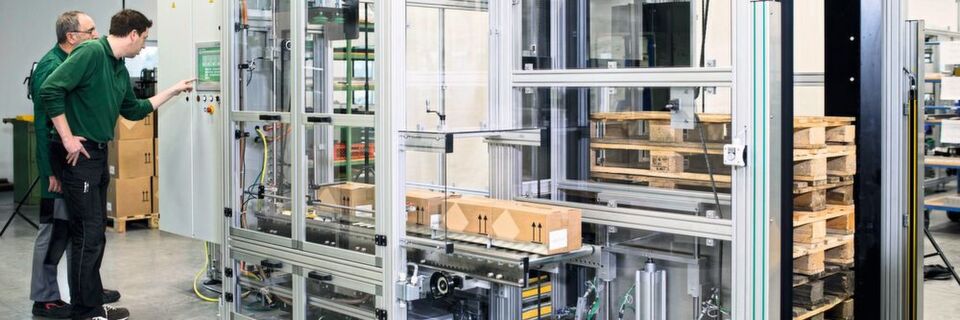 E & V Systeme hat eine Verpackungsmaschine mit einem Pick-and-Place-Palettierroboter entwickelt, der befüllte und verschlossene Kartons schnell und geordnet auf Paletten ablegt. E & V Systeme hat eine Verpackungsmaschine mit einem Pick-and-Place-Palettierroboter entwickelt, der befüllte und verschlossene Kartons schnell und geordnet auf Paletten ablegt.