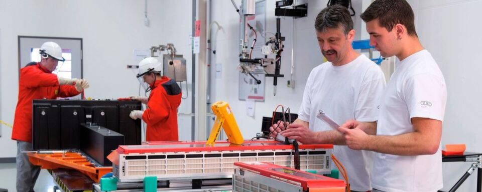 Im Vordergrund prüfen Mitarbeiter Spannungsabgriffe von Batteriezellen, im Hintergrund findet die elektrische Endmontage einer Batterie für den R8 E-Tron statt. Im Vordergrund prüfen Mitarbeiter Spannungsabgriffe von Batteriezellen, im Hintergrund findet die elektrische Endmontage einer Batterie für den R8 E-Tron statt.