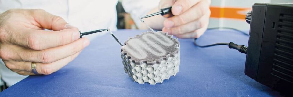 Der 3D-gedruckte Multi-Material-Leichtbaudemonstrator besteht aus kohlenstofffaserverstärktem thermochromem Kunststoff und Titan-Grundstruktur. Durch elektrische Aktivierung wird Wärme in der Kohlenstofffaser induziert und ein Farbwechsel im Kunststoff herbeigeführt. Der 3D-gedruckte Multi-Material-Leichtbaudemonstrator besteht aus kohlenstofffaserverstärktem thermochromem Kunststoff und Titan-Grundstruktur. Durch elektrische Aktivierung wird Wärme in der Kohlenstofffaser induziert und ein Farbwechsel im Kunststoff herbeigeführt.