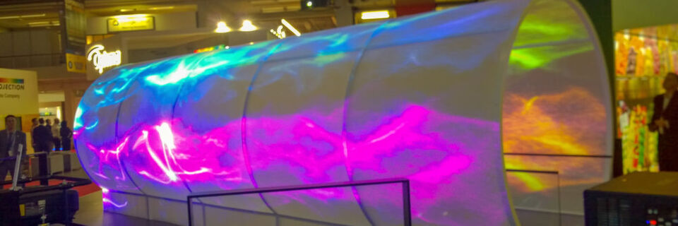 Der Blickfang auf dem Epson-Stand: Der interaktive Tunnel EpsonVortex, entwickelt von Crucial FX. Die Projektion übernehmen 16 EB-L1755U-Laserprojektoren mit ELPLU03 Weitwinkelobjektiven. Kinect-Sensoren erfassen die Personen, die durch den Tunnel gehen, die Umrisse der Menschen werden nahezu in Echtzeit in die Projektion integriert. Der Blickfang auf dem Epson-Stand: Der interaktive Tunnel EpsonVortex, entwickelt von Crucial FX. Die Projektion übernehmen 16 EB-L1755U-Laserprojektoren mit ELPLU03 Weitwinkelobjektiven. Kinect-Sensoren erfassen die Personen, die durch den Tunnel gehen, die Umrisse der Menschen werden nahezu in Echtzeit in die Projektion integriert.