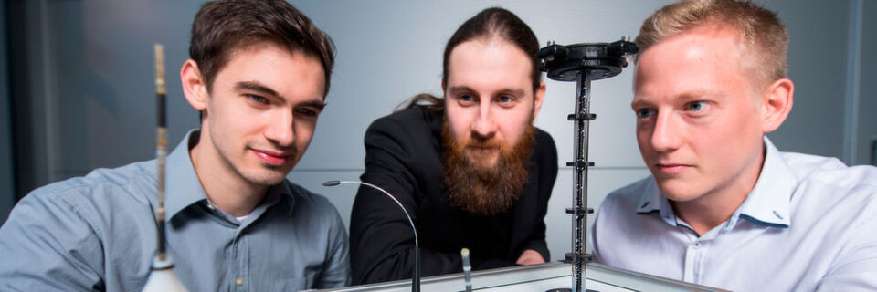 Die Doktoranden Dominik Scholtes (l.), Rouven Britz und Yannik Goergen (r.) aus Prof. Stefan Seeleckes Team mit Prototypen der biegsamen Roboterarme, die auf der Hannover Messe zu sehen sein werden. Die Doktoranden Dominik Scholtes (l.), Rouven Britz und Yannik Goergen (r.) aus Prof. Stefan Seeleckes Team mit Prototypen der biegsamen Roboterarme, die auf der Hannover Messe zu sehen sein werden.