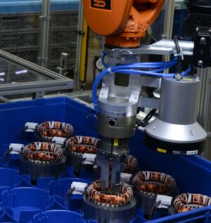 Mit einem Mehrfachgreifer entnimmt der Kuka Roboter die Statoren aus den Kleinladungsträgern. Mit einem Mehrfachgreifer entnimmt der Kuka Roboter die Statoren aus den Kleinladungsträgern.