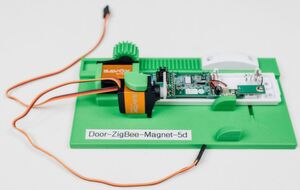 Aufnahmemodul für einen Tür-/ Fenster-Sensor. Das Modul enthält den Sensor selbst und die Elektromechanik zu dessen programmgesteuerter Bedienung. Aufnahmemodul für einen Tür-/ Fenster-Sensor. Das Modul enthält den Sensor selbst und die Elektromechanik zu dessen programmgesteuerter Bedienung.