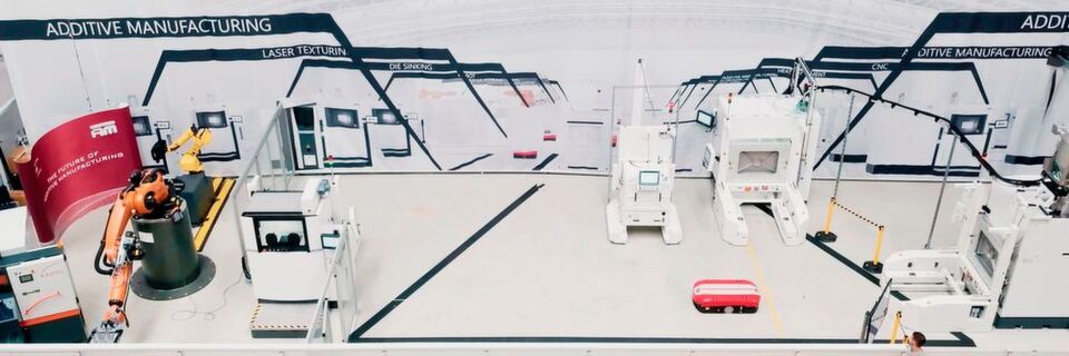 Die aufgebaute Pilotanlage des NextGenAM-Projekts zur automatisierten additiven Fertigung im Detail, v.l.n.r.: Bandsäge, Kuka-Roboter, dahinter: 3D-Vermessungsstation (Geometrisch Optische Messung / GOM), Rüststation, Auspackstation, davor: Transportfahrzeug (AGV), EOS M 400-4, nicht im Bild: Pulverstation IPM M Powder Station L von EOS. Die aufgebaute Pilotanlage des NextGenAM-Projekts zur automatisierten additiven Fertigung im Detail, v.l.n.r.: Bandsäge, Kuka-Roboter, dahinter: 3D-Vermessungsstation (Geometrisch Optische Messung / GOM), Rüststation, Auspackstation, davor: Transportfahrzeug (AGV), EOS M 400-4, nicht im Bild: Pulverstation IPM M Powder Station L von EOS.