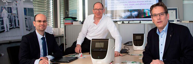 Professor Erik Schweickert MdL (ganz rechts) machte sich bei Hahn-Schickard selbst ein Bild vom Testsystem, das nun für den Corona-Nachweis weiterentwickelt wird. Dr. Daniel Mark von Spindiag (li.) und Hahn-Schickard-Institutsleiter Professor Roland Zengerle führten das System vor Professor Erik Schweickert MdL (ganz rechts) machte sich bei Hahn-Schickard selbst ein Bild vom Testsystem, das nun für den Corona-Nachweis weiterentwickelt wird. Dr. Daniel Mark von Spindiag (li.) und Hahn-Schickard-Institutsleiter Professor Roland Zengerle führten das System vor