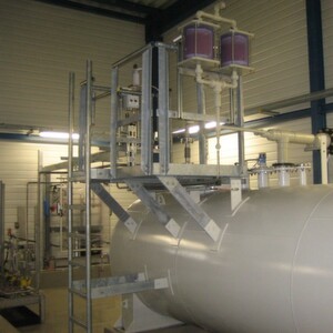 Teil einer Dosieranlage zur Kühlwasserkonditionierung: Über einen Befüllschrank (hinten) pumpt ein Tankfahrzeug Schwefelsäure von außerhalb des Gebäudes in den Lagerbehälter (rechts). Danach fördern zwei Dosierpumpen (links) die Chemikalie aus dem Behälter in einen statischen Mischer, wo sie mit Wasser vermischt wird. Von dort gelangt das Medium in das Kühlwasser. Klar erkennbar sind zwei Kieselgelfilter oben auf dem Bedienpodest. Teil einer Dosieranlage zur Kühlwasserkonditionierung: Über einen Befüllschrank (hinten) pumpt ein Tankfahrzeug Schwefelsäure von außerhalb des Gebäudes in den Lagerbehälter (rechts). Danach fördern zwei Dosierpumpen (links) die Chemikalie aus dem Behälter in einen statischen Mischer, wo sie mit Wasser vermischt wird. Von dort gelangt das Medium in das Kühlwasser. Klar erkennbar sind zwei Kieselgelfilter oben auf dem Bedienpodest.