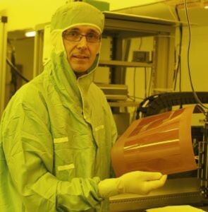 IBM scientist Roger Dangel holding a thin film polymer waveguide: IBM is experimenting with waveguides as a way to integrate silicon photonic chips into data center systems. IBM scientist Roger Dangel holding a thin film polymer waveguide: IBM is experimenting with waveguides as a way to integrate silicon photonic chips into data center systems.